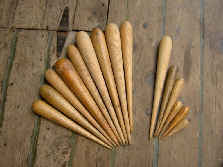 wooden spikes with round backs in various sizes arranged in a fan shape on wood floor