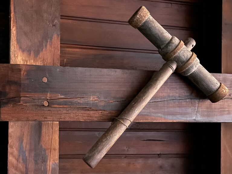 wooden mallet with rusted bindings on a long head